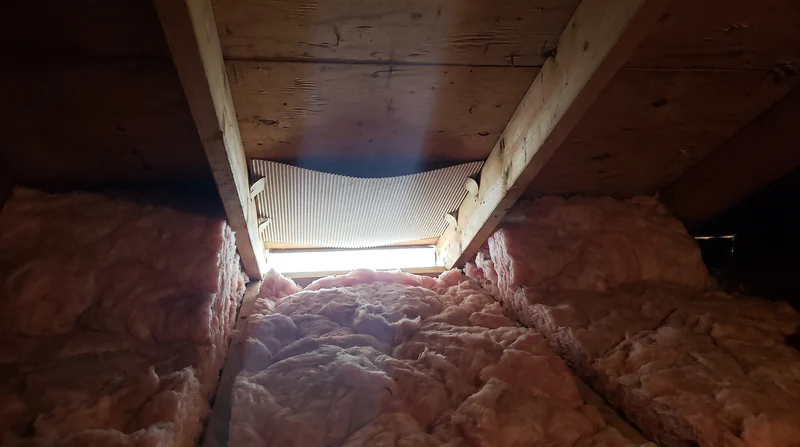 Attic interior showing a ventilation baffle keeping the soffit intake vent clear