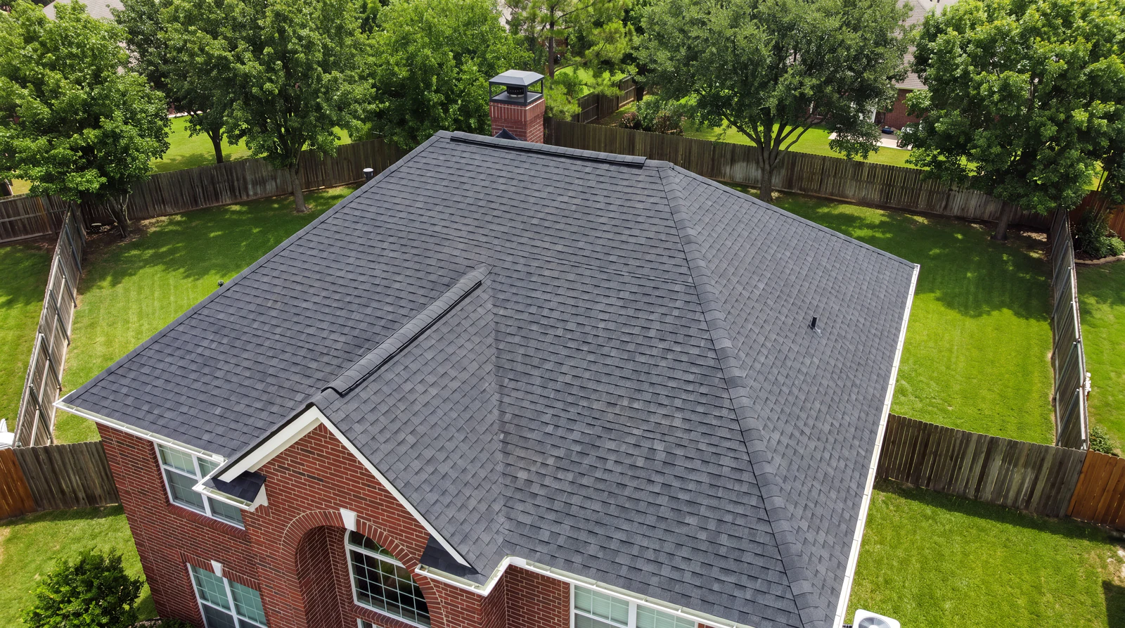 Aerial photo of a brick home with a dark architectural shingle roof replacement finished by GSP Exterior Works