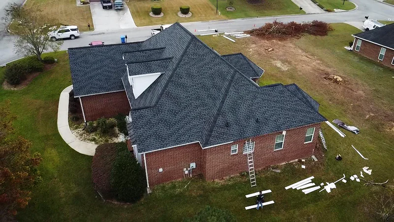 Brick ranch home mid roof replacement with materials staged and ladder in place